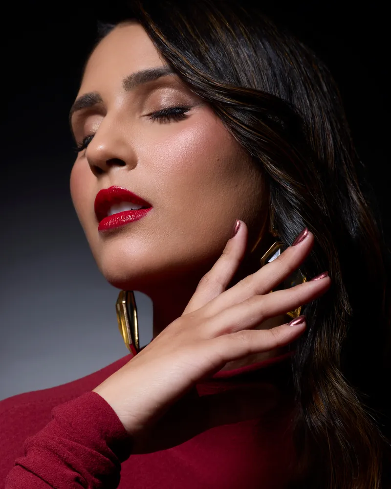 Retrato em close da Dra. Raissa Alana, de olhos fechados, com brinco dourado e batom vermelho